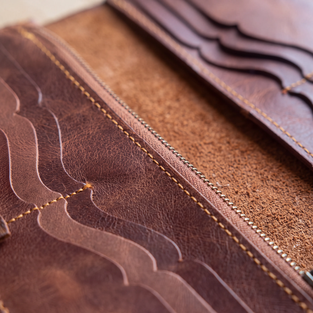 Close-up of the Velora Maren Continental Wallet's interior, showing the zip compartment edge with metal zipper teeth, layered card-slot stitching, and the natural grain of the leather.